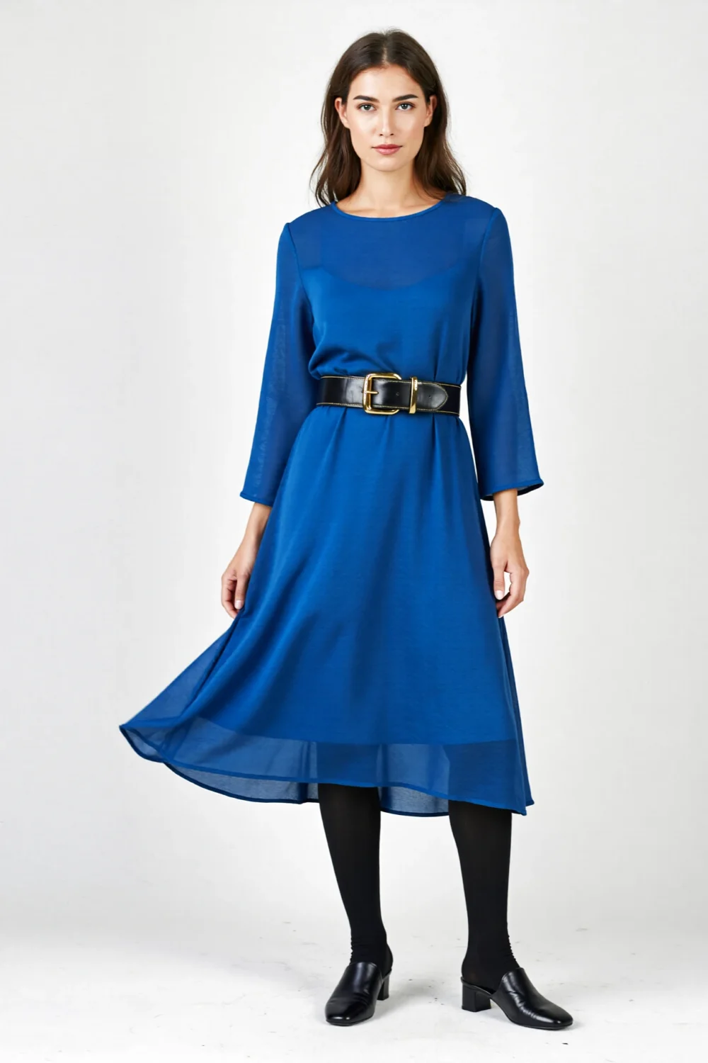 Blue layered dress cinched with black belt over tights, styled with black loafers for a structured, polished silhouette