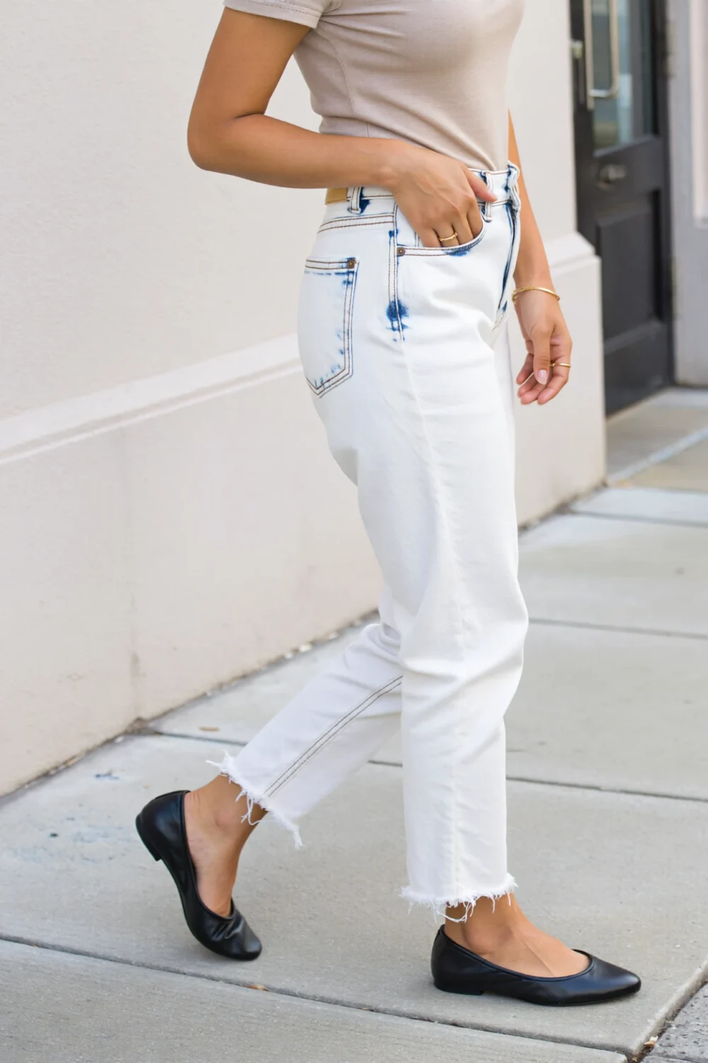 Black ballet flats paired with cropped white denim jeans and a beige tee, creating a crisp, casual Paris-inspired street look.