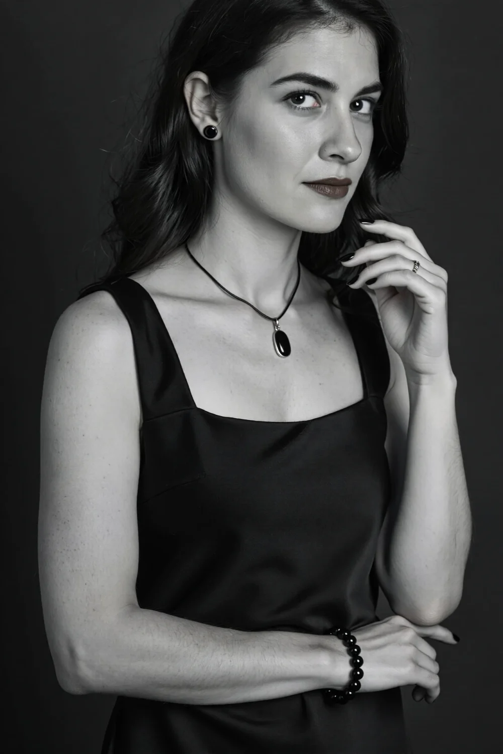 Woman in black LBD wearing black onyx stud earrings, oval onyx pendant and beaded bracelet for a moody, modern monochrome look