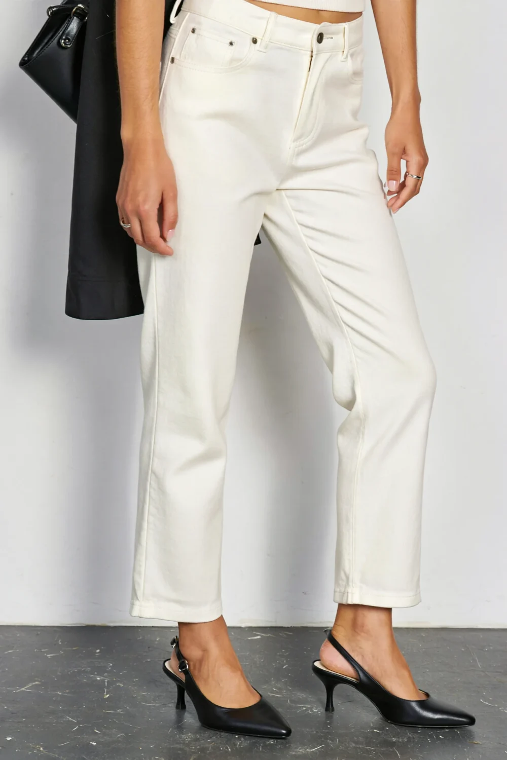 Black slingback pumps with bright white cropped trousers and a black bag, creating a sharp, modern, elongating look.