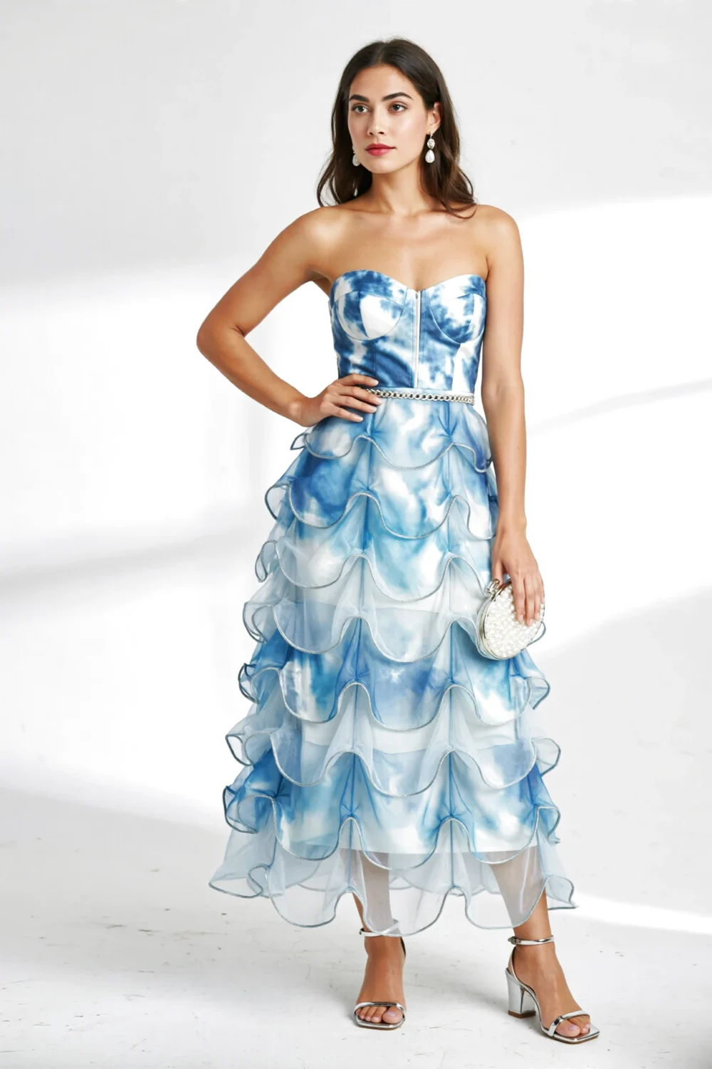 Strapless tea-length gown in sky-to-ice blue with petal organza tiers and silver piping, styled with mirror-silver sandals and clutch