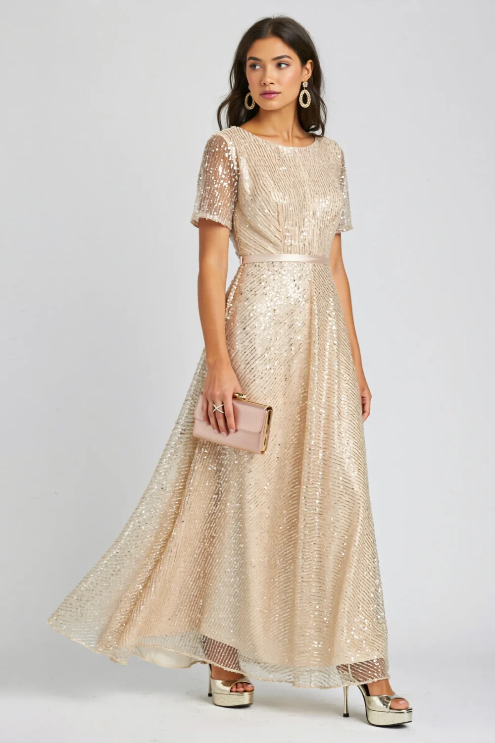 Champagne sequin gown with bateau neckline, cap sleeves, and flowing godet skirt, styled with a slim waist belt and clutch.