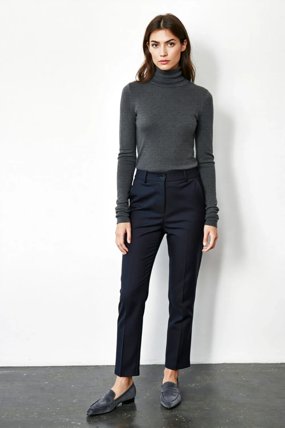 Woman in a charcoal turtleneck and navy cigarette pants with suede loafers, creating a sleek, city-ready monochrome silhouette