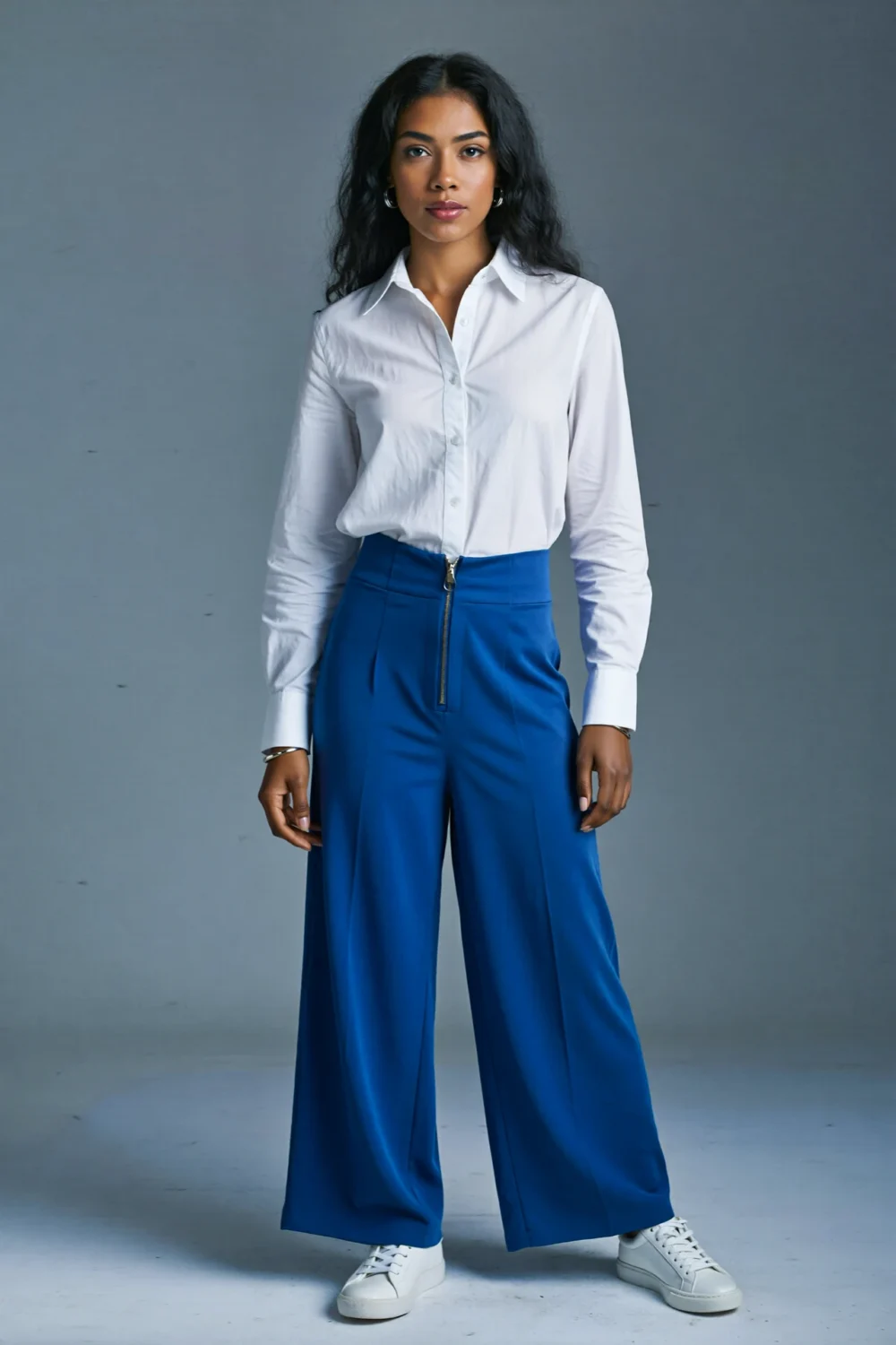 Woman in crisp white shirt and cobalt wide-leg trousers styled with white sneakers for a clean, confident statement look
