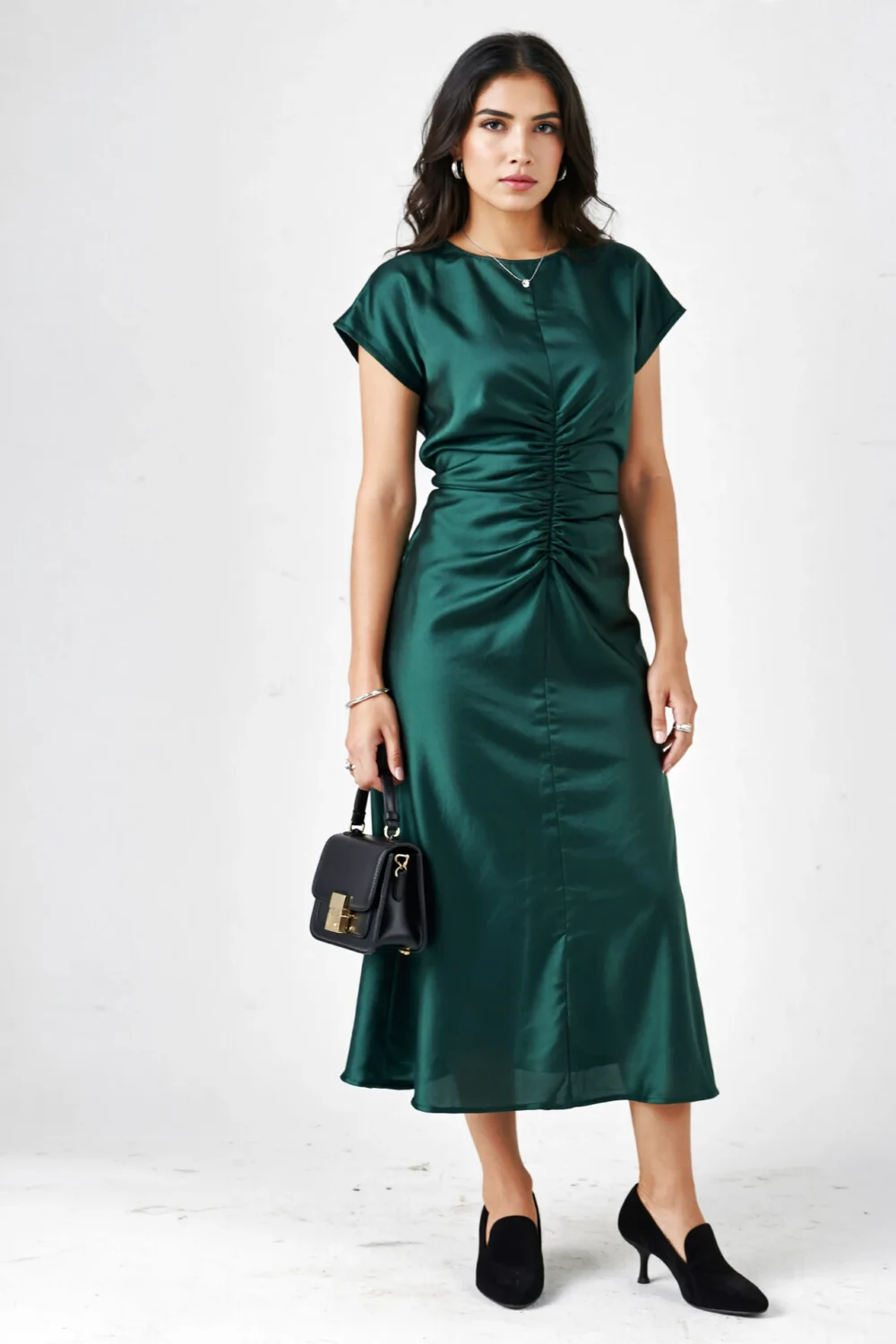 Woman in a dark green crepe midi dress styled with black suede pumps and a black handbag for a luxe, polished evening look