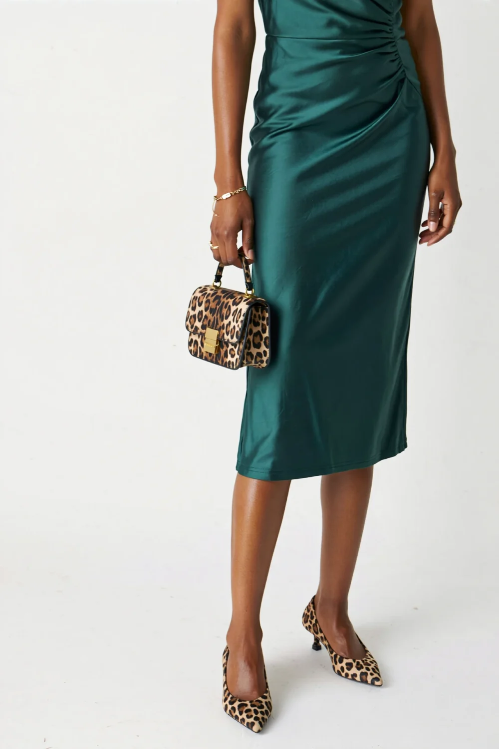 Dark green satin cocktail dress styled with leopard print pumps and matching clutch, creating a chic fashion-forward neutral contrast