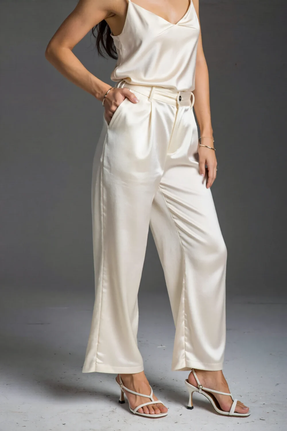 Satin white pants styled with delicate slingback heels and a streamlined cream top, creating a romantic, refined look with soft shine.