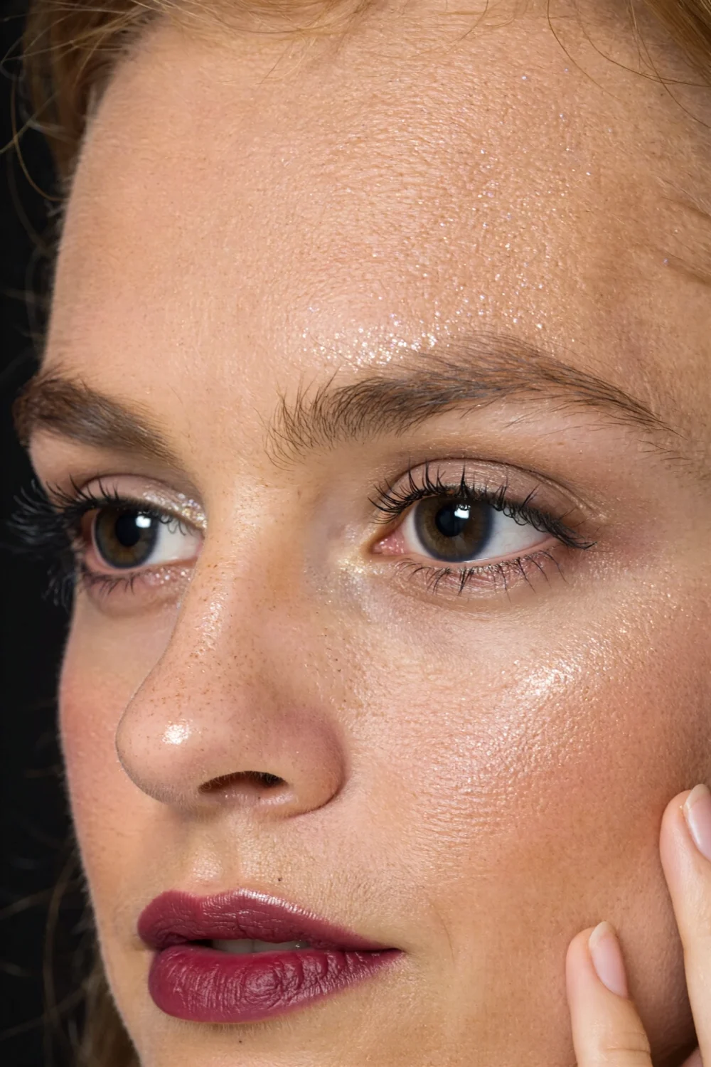 Close-up model wearing charcoal smoky liner and mascara for wide-awake eyes, subtle shimmer and festive office-safe berry lip.