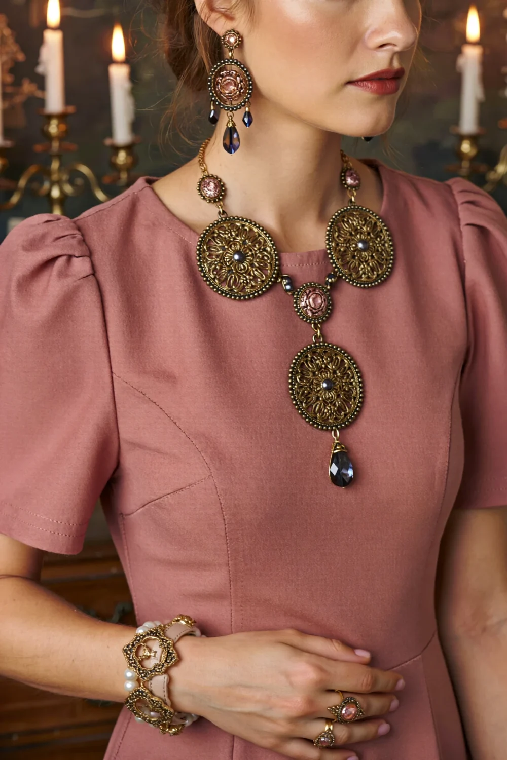 Dusty pink dress with antique gold and smoky crystal jewelry, featuring ornate earrings, necklace, bracelet, and ring accents, vintage-inspired