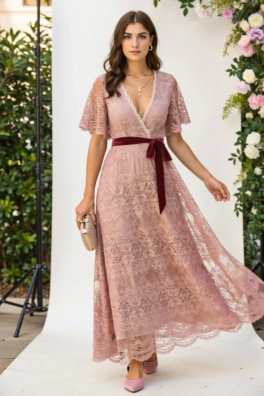 Model in dusty rose lace maxi dress with surplice neckline, fluted sleeves, velvet sash, and flowing A-line skirt for elegant photoshoots
