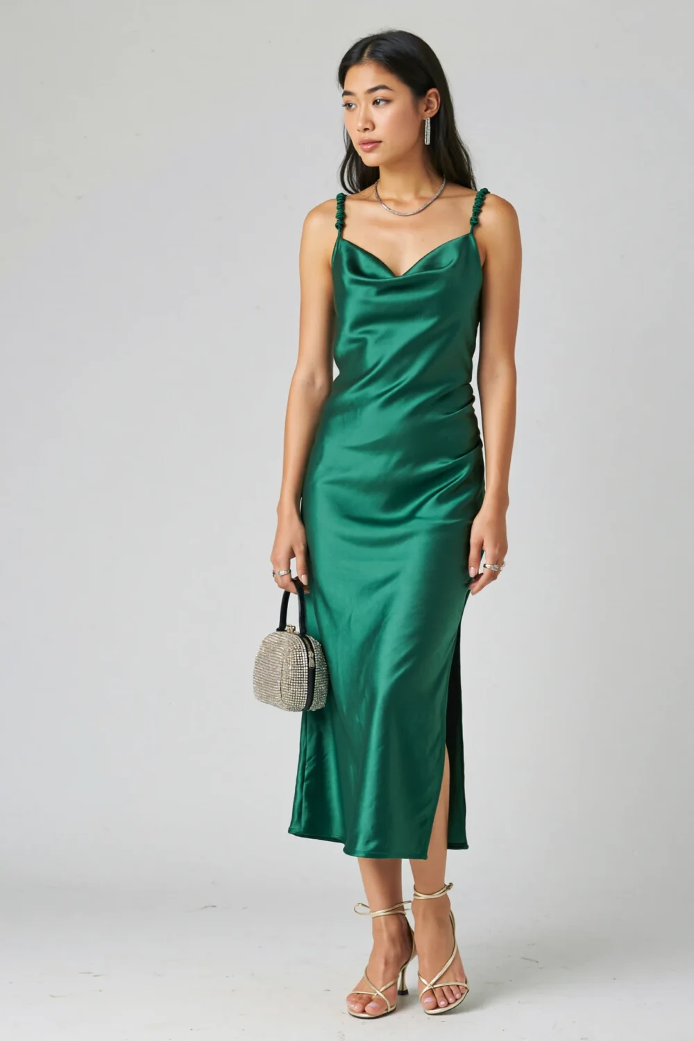 Model in emerald silk charmeuse slip dress with cowl neckline, crystal mini bag, and champagne strappy heels, editorial look