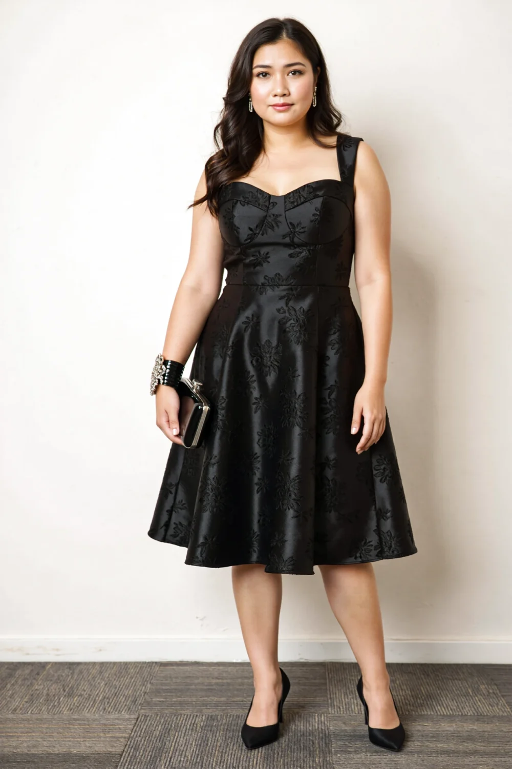 Woman wearing a black fit-and-flare brocade cocktail dress at midi length, black heels and an elegant jeweled bracelet clutch.