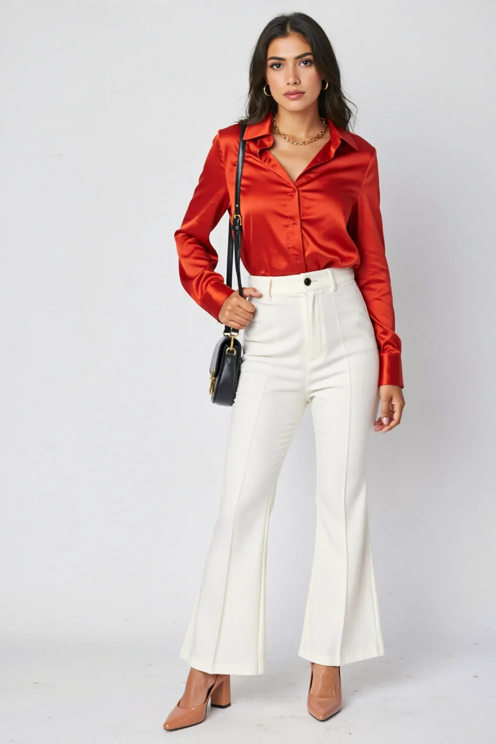 Bold red satin shirt tucked into high-waisted white flares, styled with nude heels and a black crossbody for a sleek look