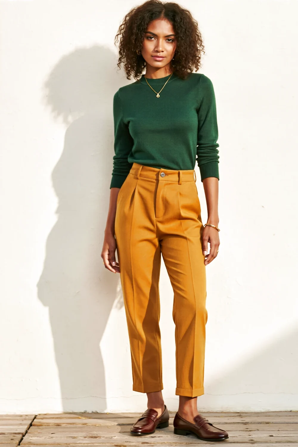 Forest green top with mustard trousers and brown loafers creates a sunny, polished color-blocked outfit with gold jewelry accents