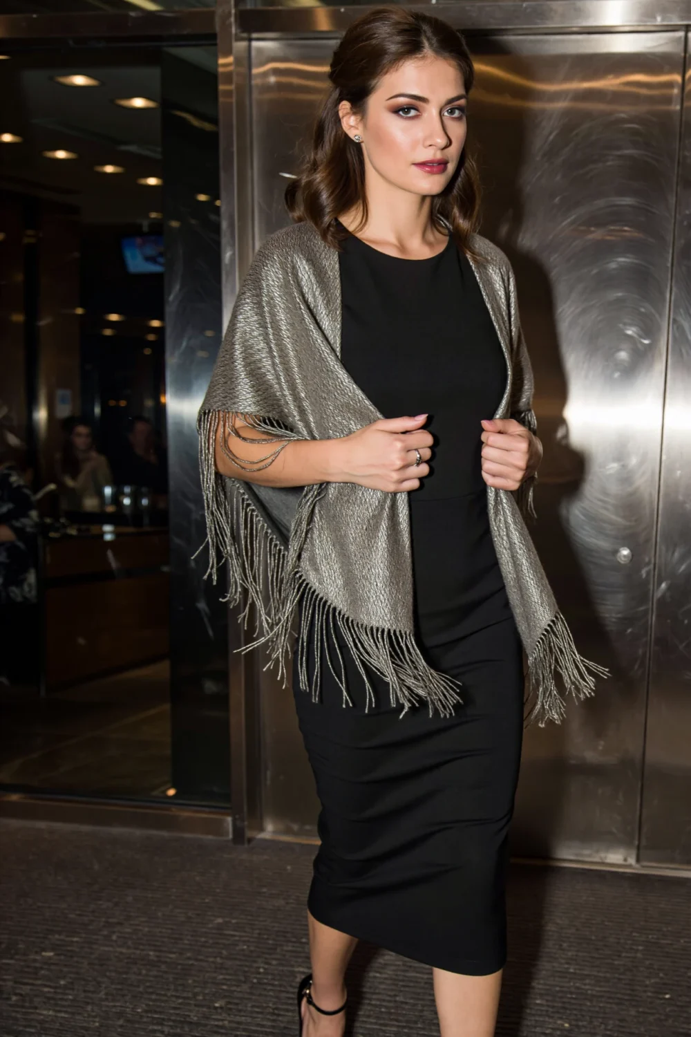 Woman in a black evening dress wearing a metallic fringed wrap that sways with movement, adding whimsical removable elegance.
