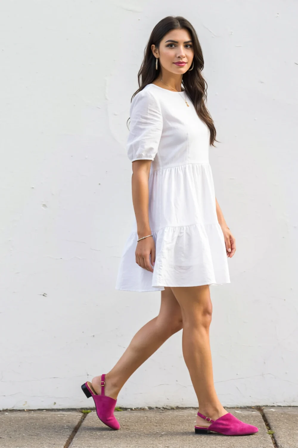 Woman in a white cotton mini dress styled with bright fuchsia backless mules for a playful, breezy summer look and pop color
