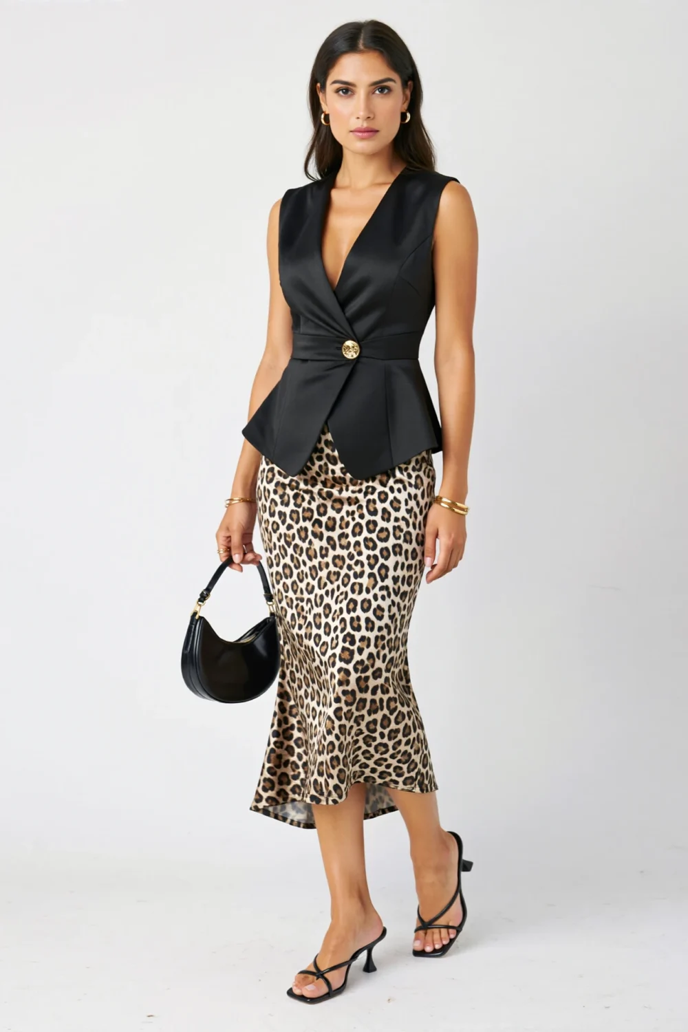 Black peplum waistcoat with gold button, leopard midi skirt, slingback heels and crescent bag create a polished gilded noir safari look