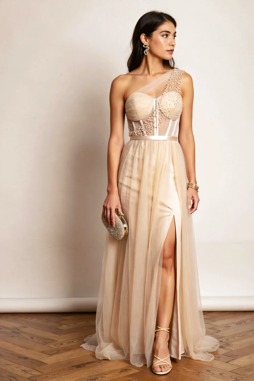 Model in champagne taupe chiffon gown with corseted bodice, embellished tulle one-shoulder strap and airy skirt with thigh slit.
