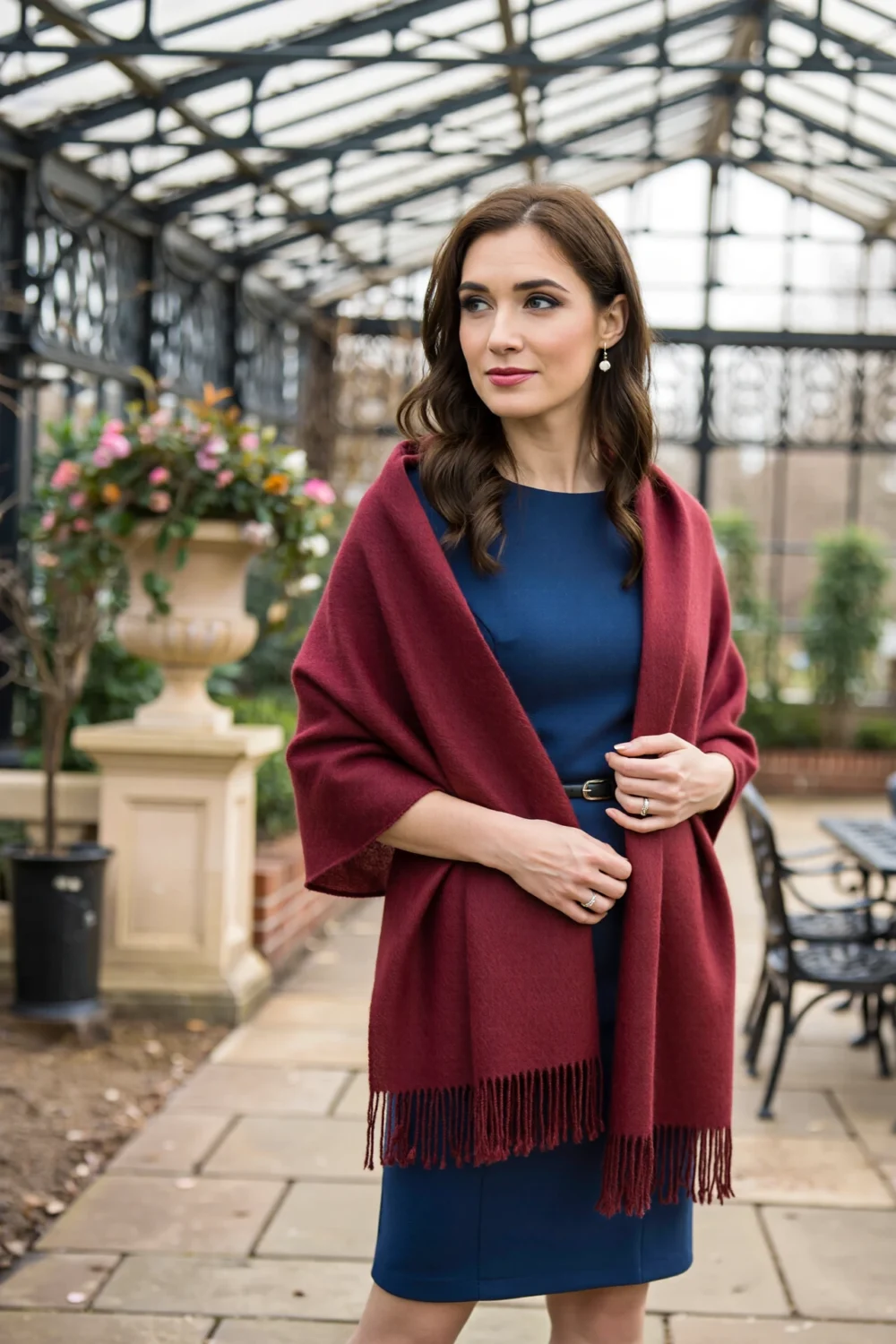 Woman in a navy dress wears a jewel-tone burgundy cashmere scarf draped over shoulders, belted and styled for versatile warmth.