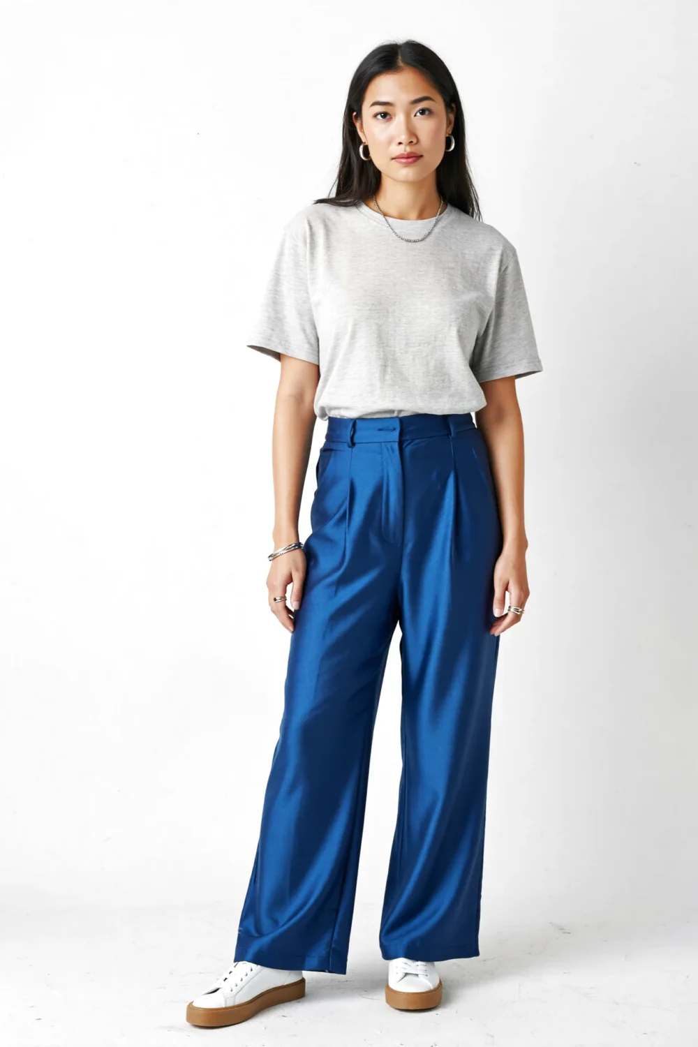 Light gray slub tee tucked into cobalt wide-leg trousers, styled with silver jewelry and white sneakers for a modern minimal look