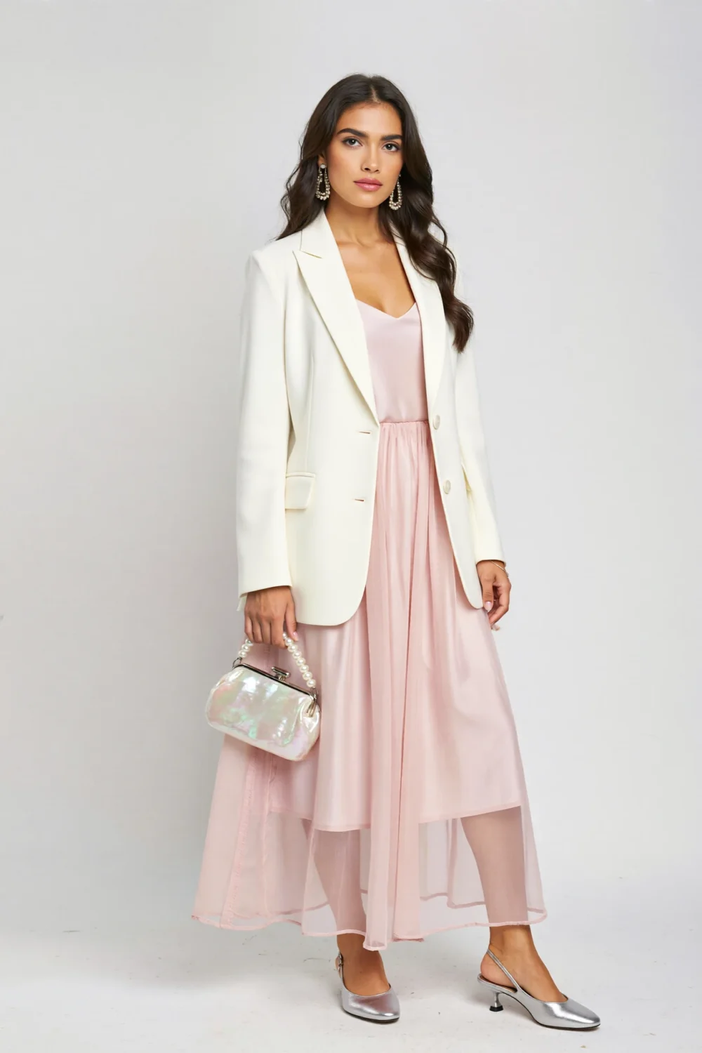Light pink midi dress styled with a white blazer, silver slingbacks, and a pearl handbag for a polished, airy layered look