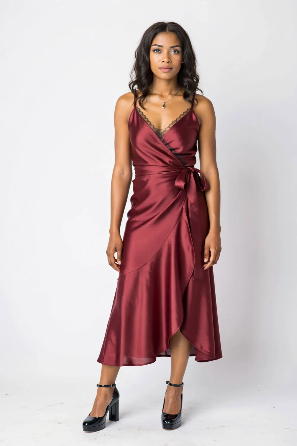 Jewel-toned wrap midi dress with soft sheen, delicate necklace, and black block heels for a polished reunion look