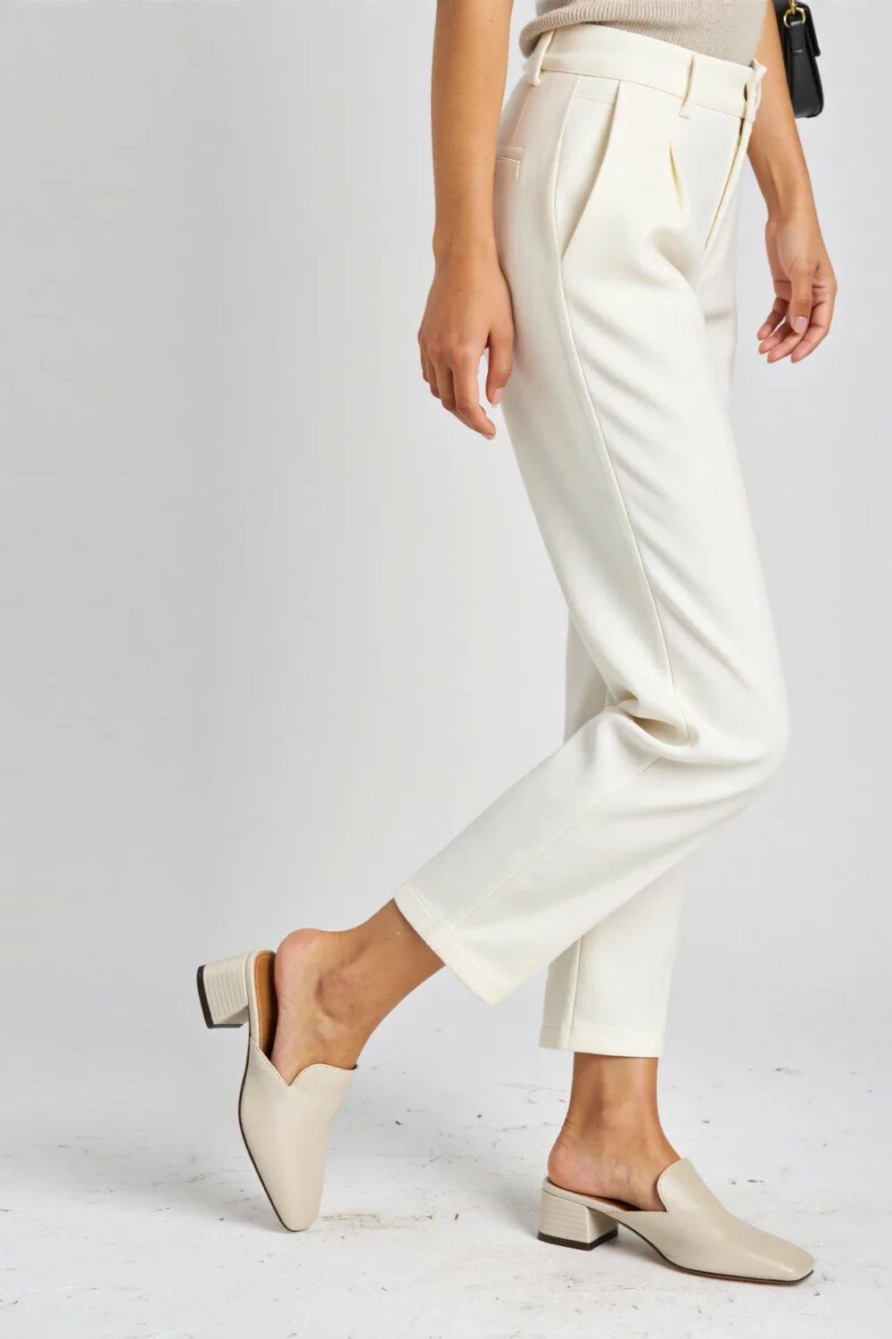 Cropped white pants paired with cream slip-on mules, square toe and low heel, creating a relaxed-chic elevated look