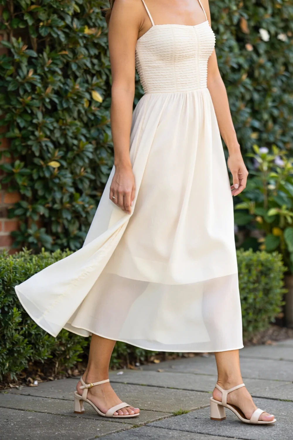 Woman in ivory midi dress wearing nude slingback kitten heels, creating a graceful daytime look with a classic refined silhouette