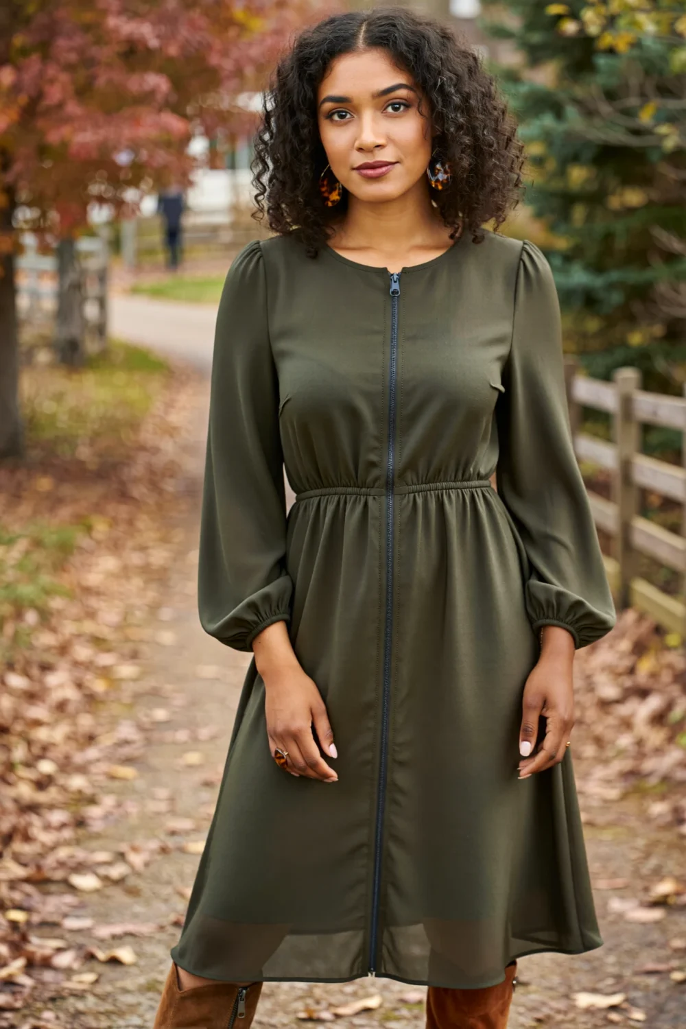 Olive midi dress with suede boots and tortoiseshell earrings, styled for a warm, sophisticated fall wedding look outdoors