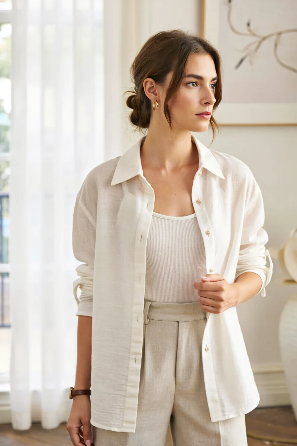 Woman wearing an open white poplin shirt over a ribbed tank with tailored trousers, creating a polished, breezy summer layered look