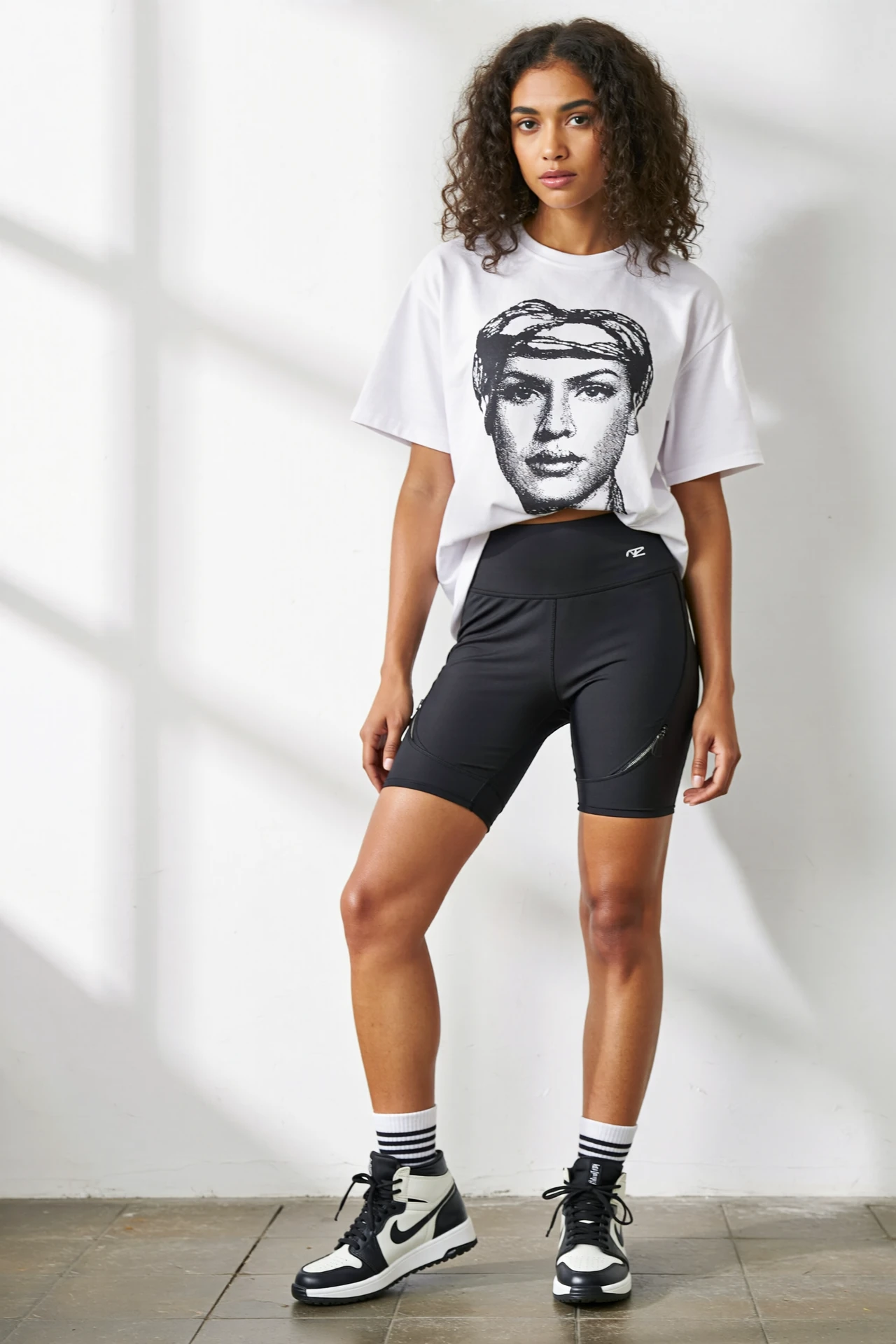 Oversized graphic tee with high-rise biker shorts and bold high-top sneakers for a sporty, breathable summer concert outfit.