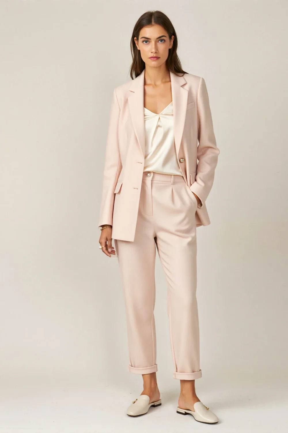 Pastel pink pantsuit with ivory shell top and low slingbacks, styled for a christening with polished, modern elegance.