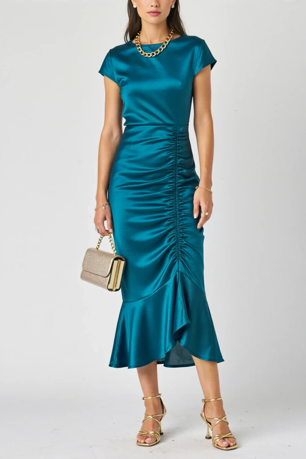 Peacock-teal midi dress with boat neckline, side ruching, gold chain necklace, champagne clutch, and pale gold heels for elegant soirée style