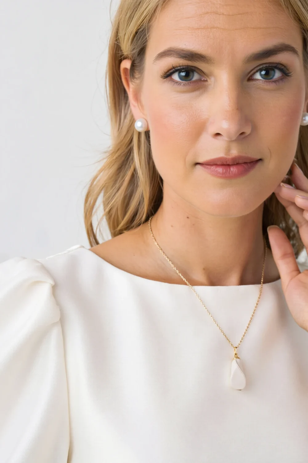 Woman in a white dress wearing pearl studs and a baroque pearl pendant, creating a soft, elegant daytime look