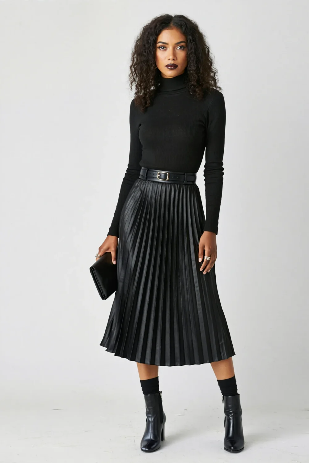 Sleek black pleated midi skirt with ribbed turtleneck and sock boots, creating a long, moody Halloween-ready silhouette