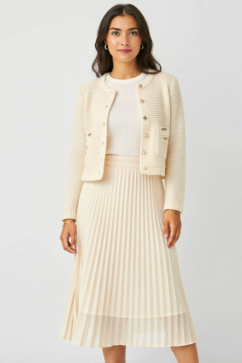 Cream pleated midi skirt with knit tee and pearl-button cropped cardigan for a soft, polished everyday look on a white background