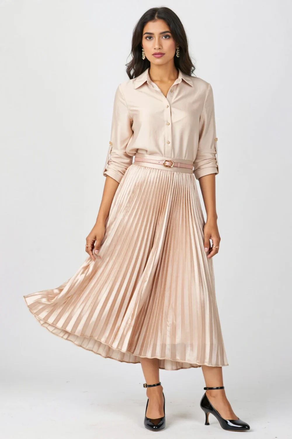 Woman in pleated satin midi skirt, cuffed silk blouse, slim belt, and black kitten heels for a soft polished outfit look