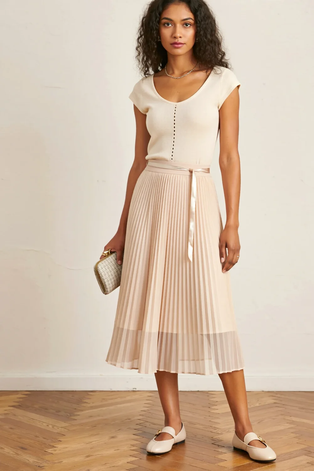 Woman in a fitted knit top, pleated midi skirt, and ballet flats for a polished smart-casual classic look, holding a clutch