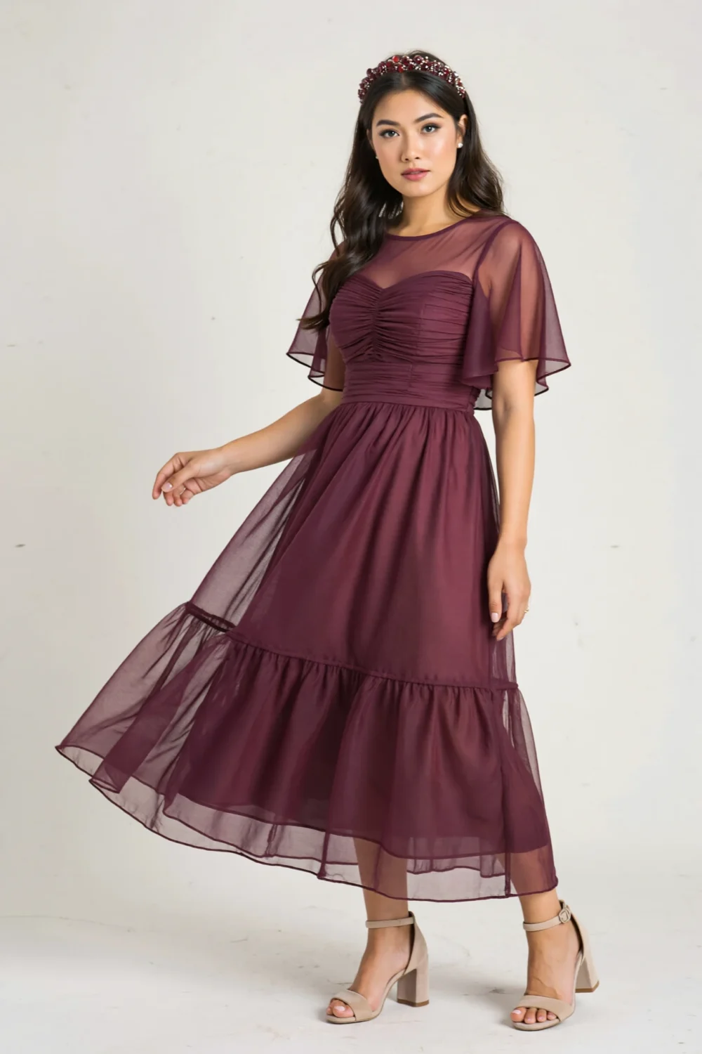Model in a plum chiffon flutter dress with sheer sleeves and layered skirt, styled for a romantic autumn wedding guest look