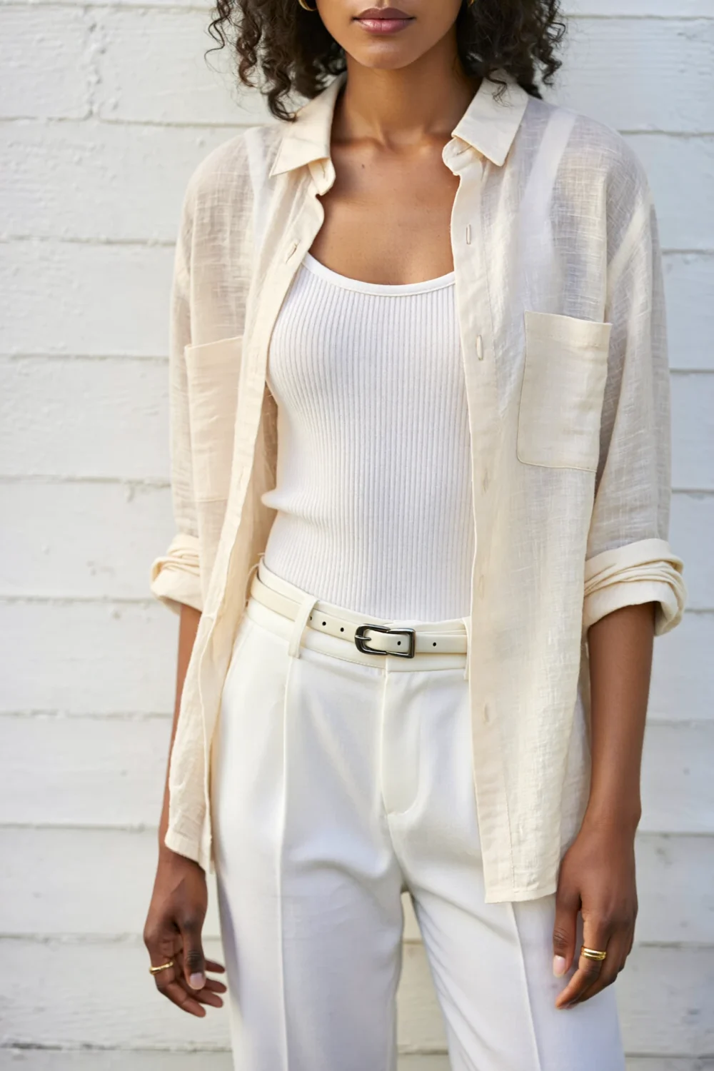 White ribbed tank under an open linen shirt, paired with high-waist pants and a slim belt for a minimal layered summer look