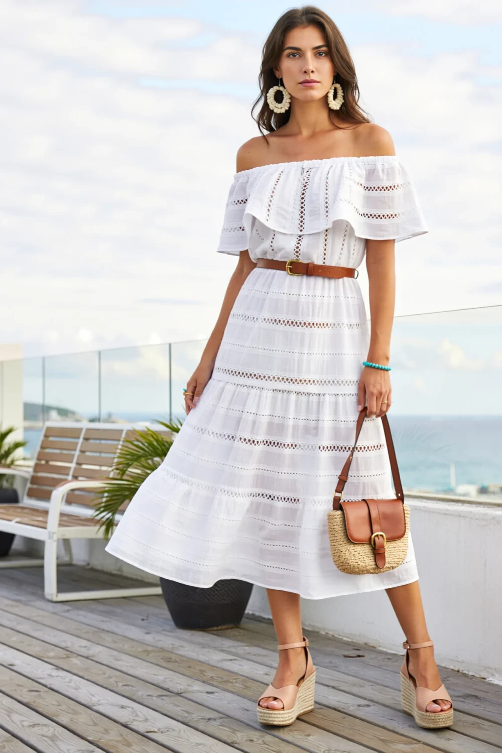 Off-the-shoulder white midi dress with ruffles, cognac belt, straw bag, and nude espadrilles for a chic resort-ready look
