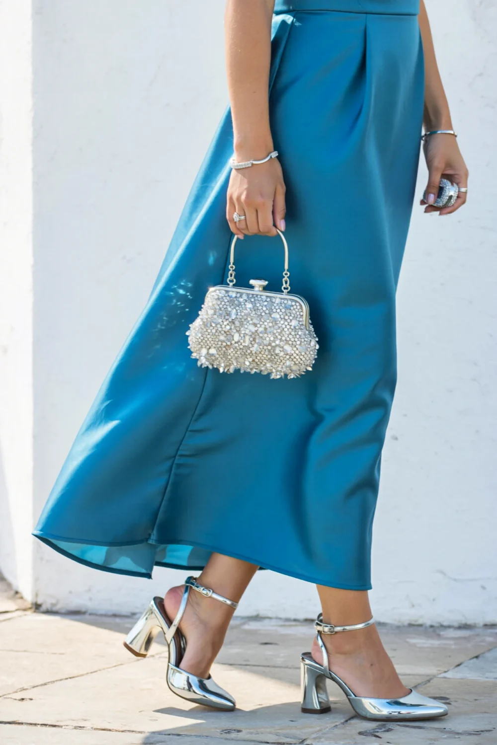 Teal blue dress with silver heels and crystal clutch, creating a polished wedding guest look with cool-toned sparkle and shine