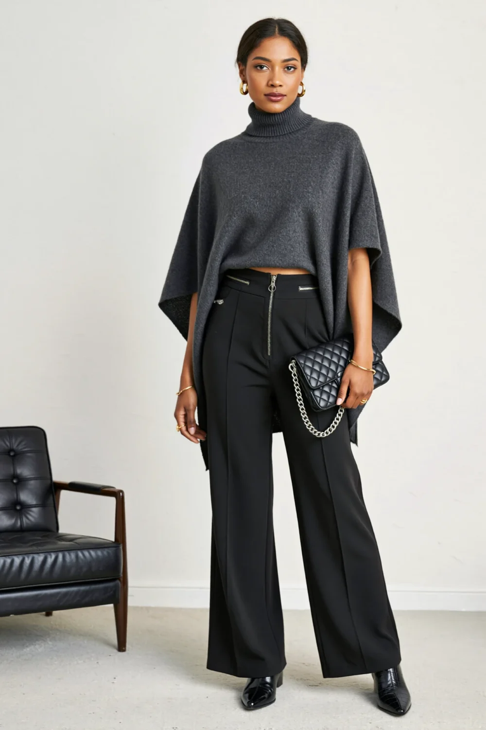 Charcoal poncho with black wide-leg trousers, pointed croc-embossed boots, and quilted clutch create a sleek, dramatic silhouette.