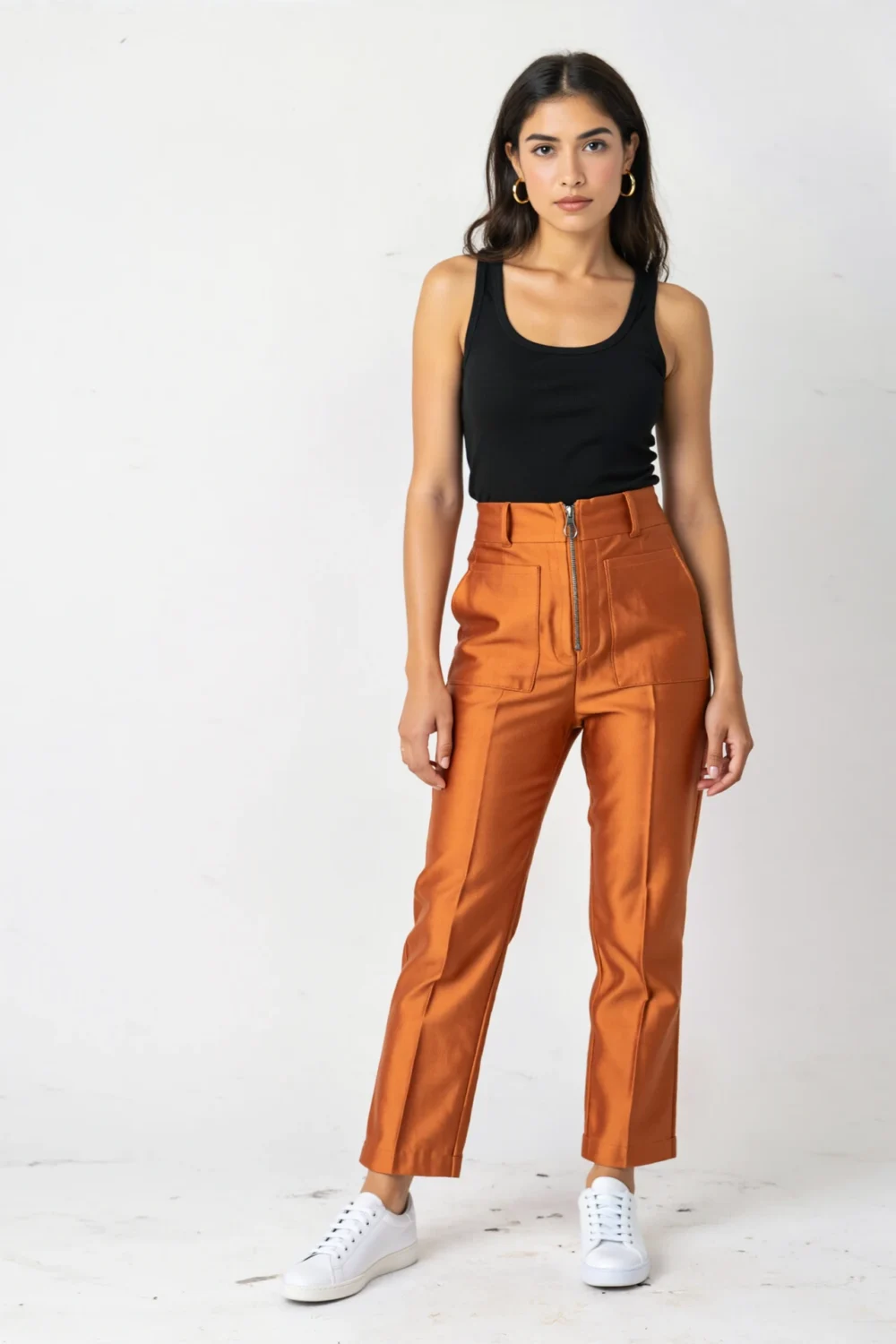 Straight-leg orange twill pants with a black ribbed tank and white sneakers, creating a sleek, bold, modern casual outfit