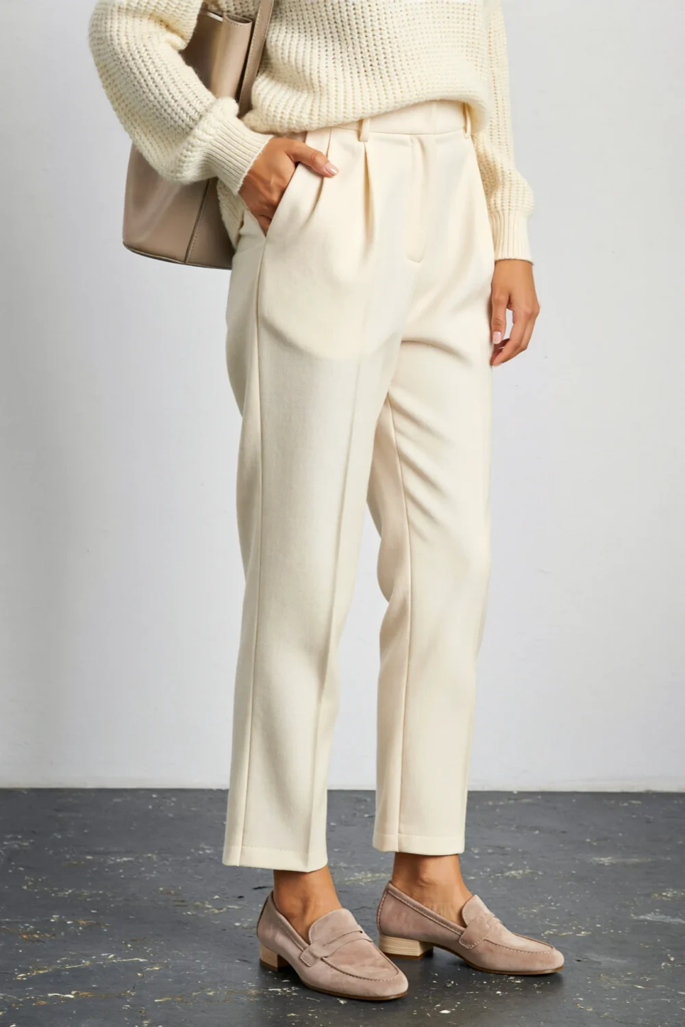 Taupe suede loafers paired with off-white tailored pants and a cream knit sweater for a refined tone-on-tone modern outfit