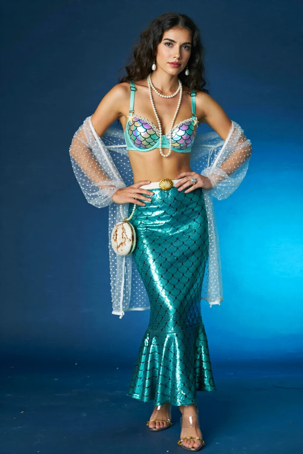 Model in a tidal glow mermaid outfit with mint iridescent bralette, seafoam sequin fishtail skirt, pearls, shell purse, and sheer shrug