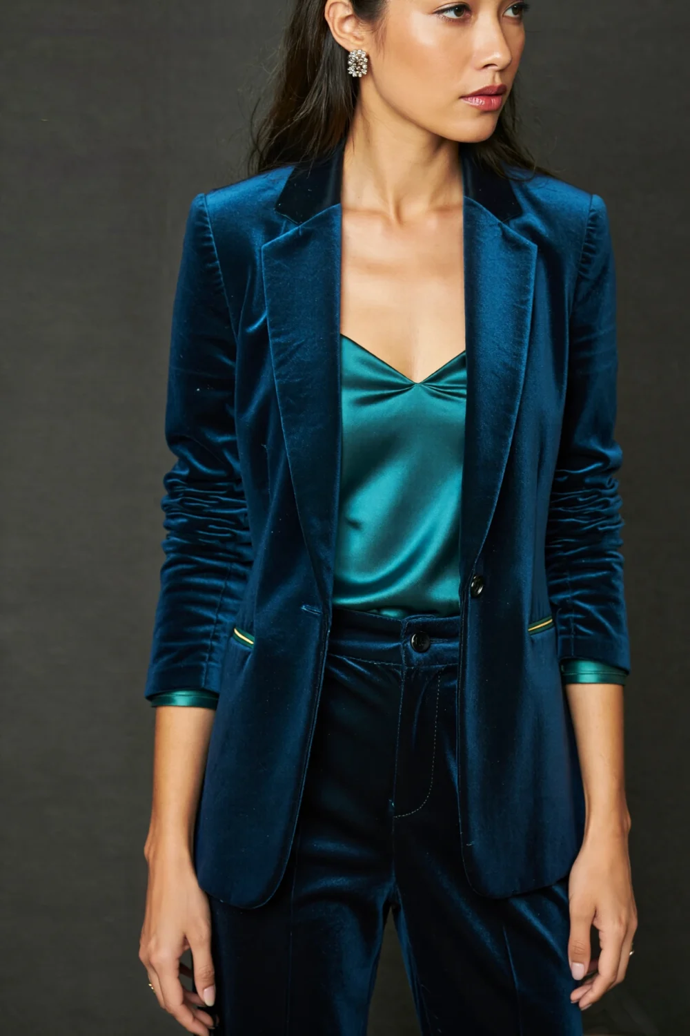 Woman in a teal velvet blazer ensemble with silk camisole and tailored trousers, styled for a classic Broadway theatre outfit with rich texture