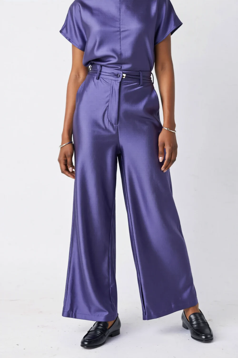 Purple satin mini shift top with wide-leg pants, belted waist and black loafers creating a sleek, modern vertical silhouette